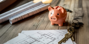 imagen de una alcancia de chancho con planos de proyectos inmobiliarios